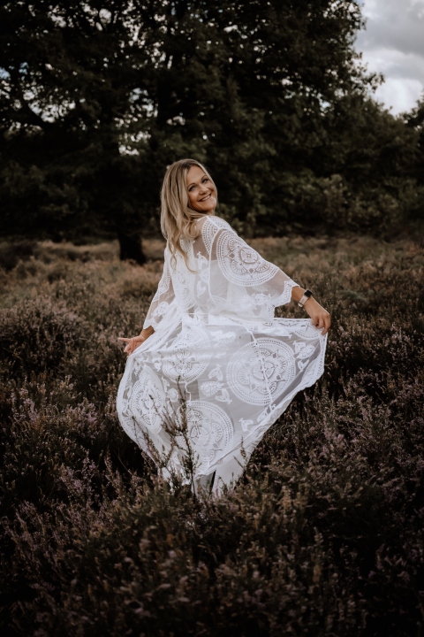 Janette Steinwand Fotografie - Frau in einem Feld spreizt mit den Händen ein weißes Kleid