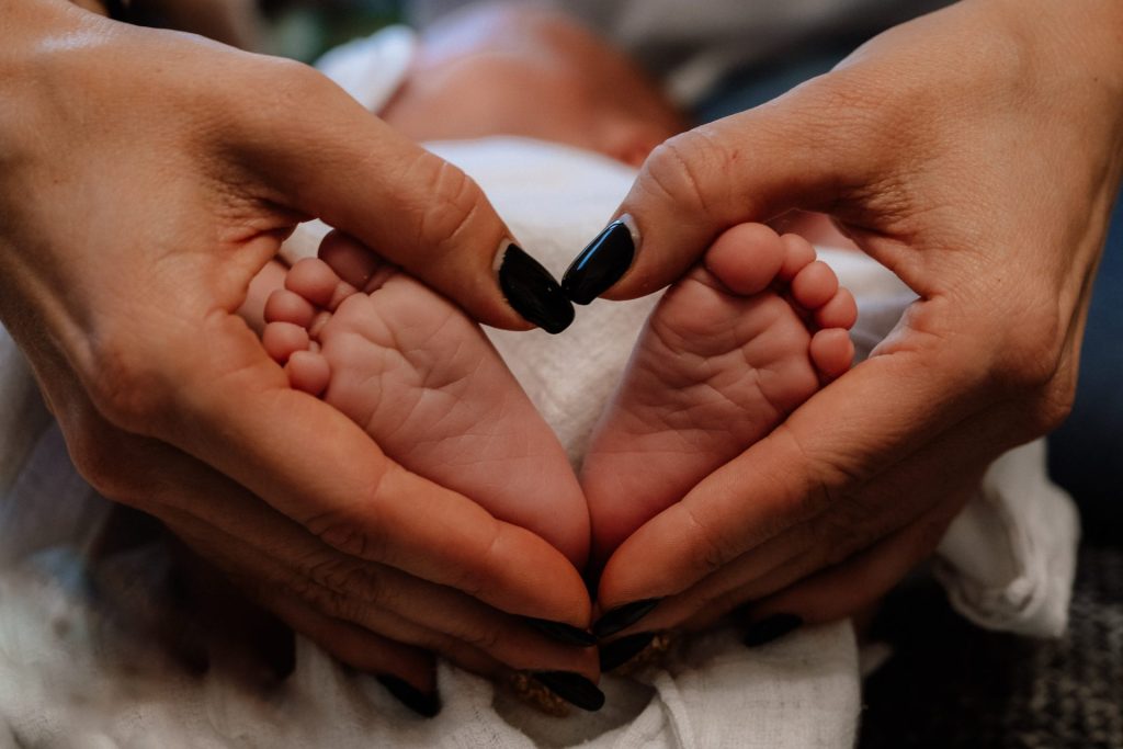 Janette Steinwand Fotografie - Die Hände einer Mutter umschließen die Füße eines Babys